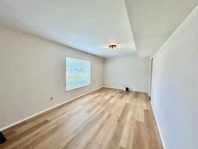 unfurnished room featuring baseboards and light wood-style floors