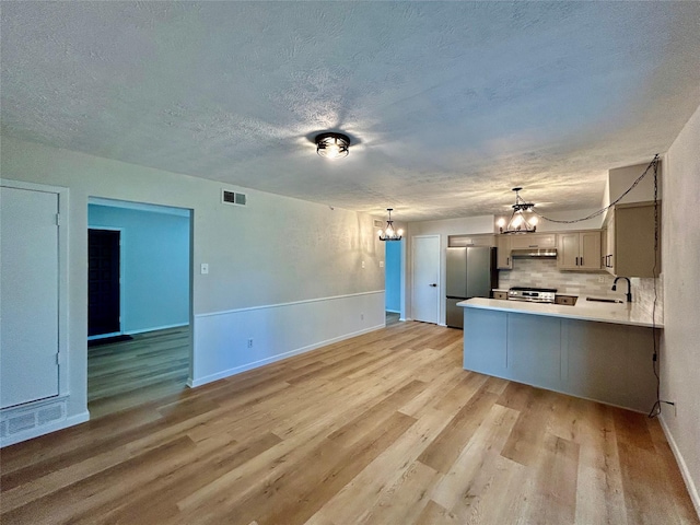 kitchen with stainless steel appliances, light wood-style flooring, visible vents, and a chandelier