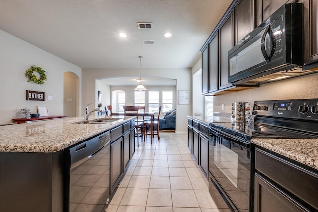 3412 San Lucas Ln, Denton, TX 76208 - kitchen featuring black appliances, a sink, arched walkways, light stone counters, and a kitchen island with sink