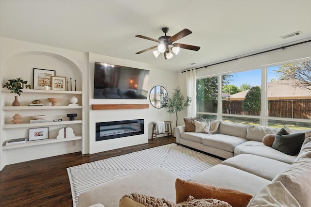 1308 Kittyhawk Dr, Little Elm, TX 75068 - living room featuring wood finished floors, ceiling fan, a glass covered fireplace, and built in shelves