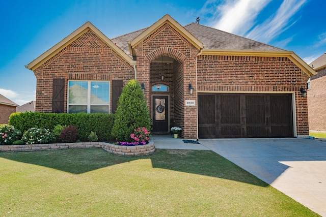 view of front of house featuring a front lawn, brick siding, roof with shingles, and driveway