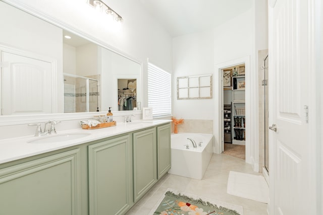 full bathroom featuring a bath, a sink, tile patterned flooring, a shower stall, and a walk in closet