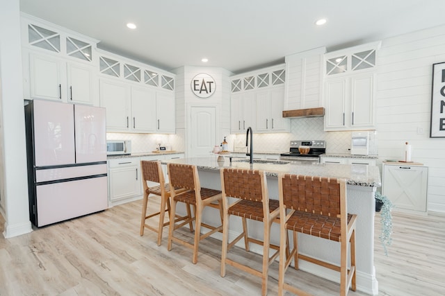 kitchen with white appliances, light wood-style floors, backsplash, and white cabinetry