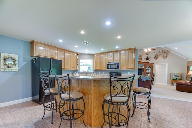 kitchen featuring light brown cabinetry, baseboards, stainless steel microwave, and black refrigerator with ice dispenser