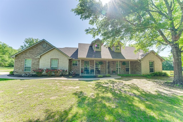 view of front of house featuring a shingled roof, a porch, a front lawn, and stone siding