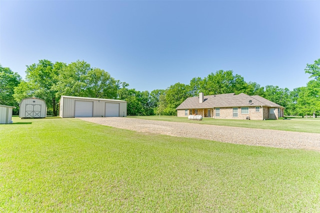 view of yard with a storage shed, a detached garage, an outbuilding, and driveway