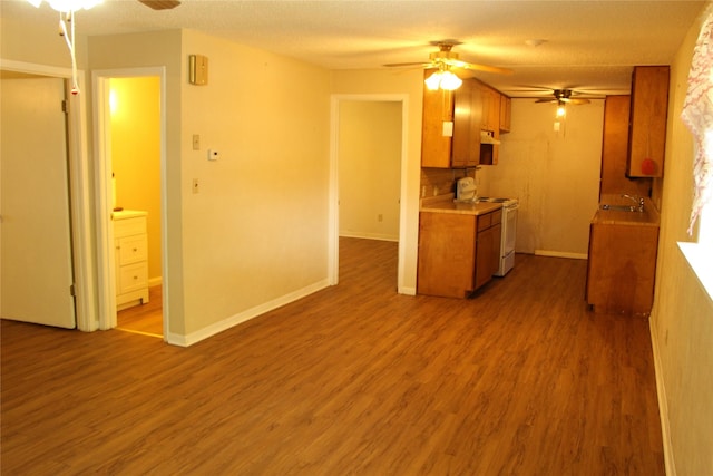 611 E 8th St, Cisco, TX 76437 - kitchen featuring dark wood-type flooring, a ceiling fan, white range with electric cooktop, and brown cabinets