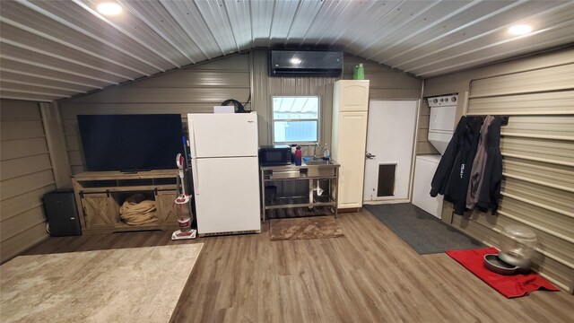 interior space featuring vaulted ceiling, wood finished floors, and a wall mounted air conditioner