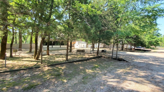 view of yard with a storage shed, an outbuilding, and fence