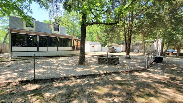 back of house with fence, an outbuilding, a sunroom, roof with shingles, and a storage unit