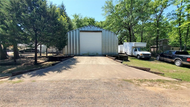 view of outdoor structure with driveway and an outbuilding