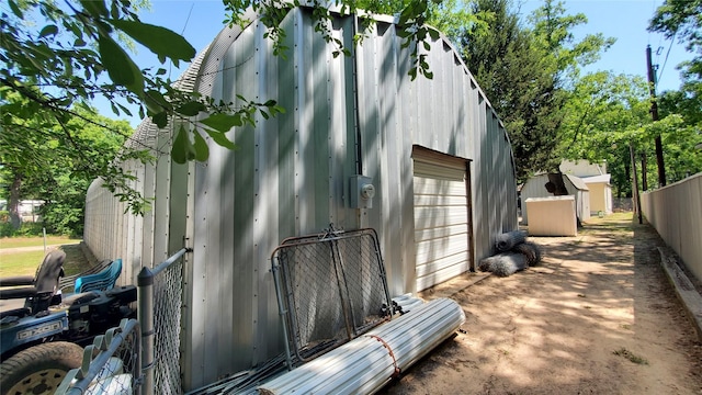 view of outdoor structure with an outbuilding, fence, and driveway