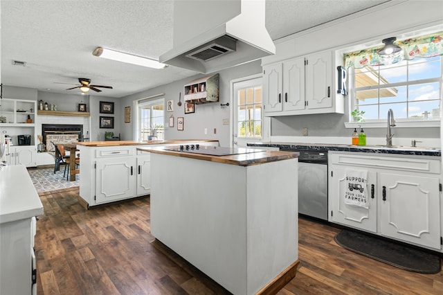 kitchen with black electric cooktop, a sink, a textured ceiling, wood counters, and a kitchen island