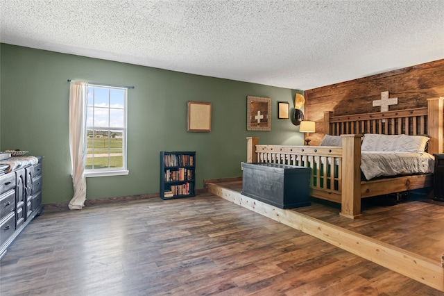 bedroom with wood finished floors, a textured ceiling, and wood walls