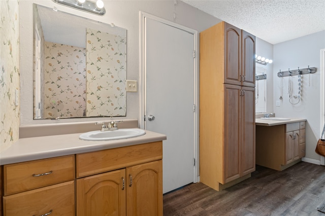 bathroom with two vanities, wood finished floors, a textured ceiling, and a sink