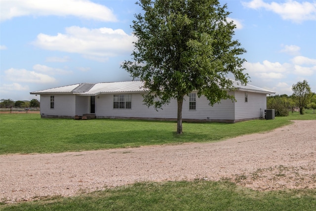 back of house featuring a lawn, central AC, and metal roof