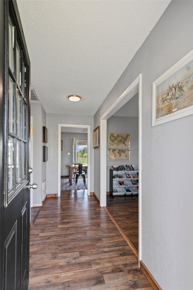 entryway with baseboards, visible vents, a textured ceiling, and dark wood-style floors