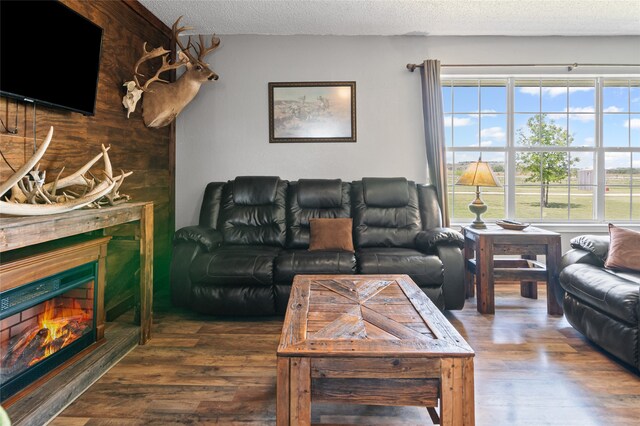 living room featuring a lit fireplace, wood finished floors, a textured ceiling, and plenty of natural light