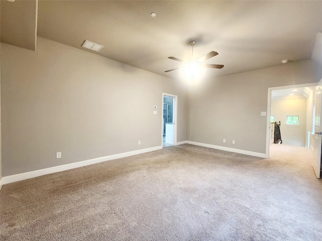 carpeted spare room with visible vents, baseboards, and ceiling fan