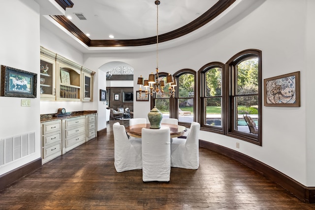 dining area featuring dark wood-style flooring, visible vents, a notable chandelier, and crown molding