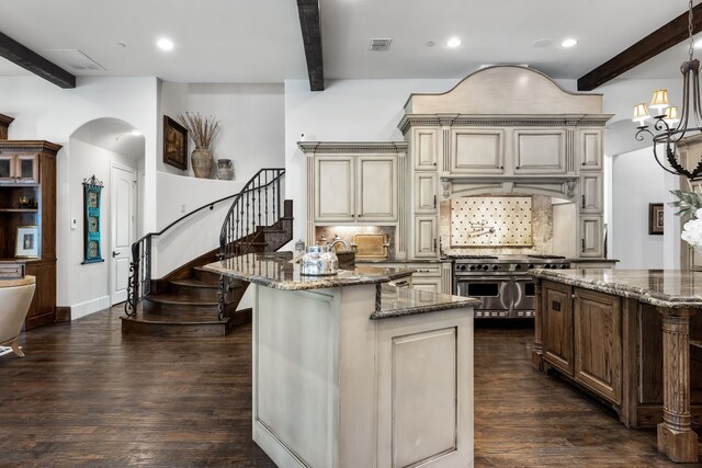 kitchen with beam ceiling, double oven range, visible vents, backsplash, and cream cabinetry