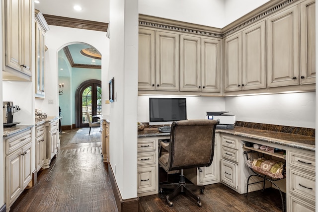 office area featuring built in desk, arched walkways, crown molding, and dark wood-style floors