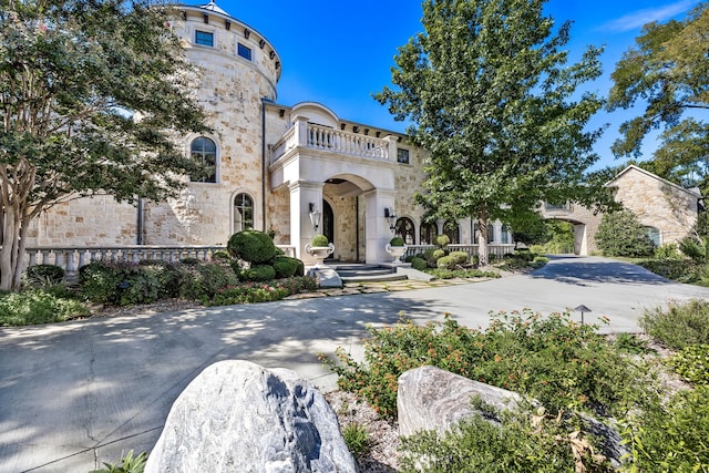 view of front facade featuring stone siding and a balcony