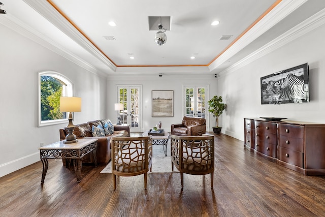living area with a raised ceiling, wood finished floors, visible vents, and baseboards