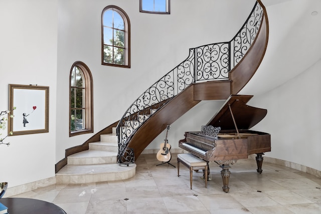 stairway featuring baseboards and a towering ceiling