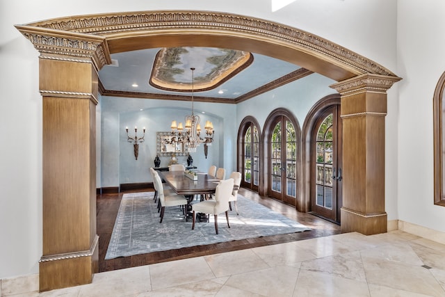 dining room featuring arched walkways, decorative columns, a notable chandelier, crown molding, and a raised ceiling