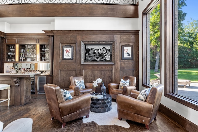 living area featuring a healthy amount of sunlight, bar, and dark wood finished floors