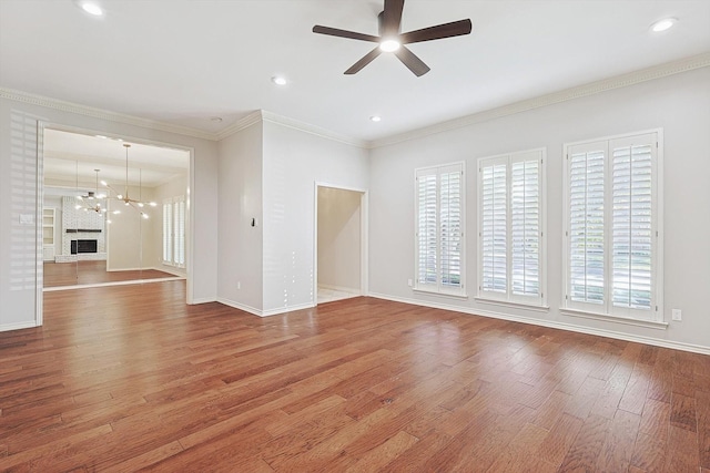 unfurnished living room with ceiling fan with notable chandelier, baseboards, wood finished floors, and a healthy amount of sunlight