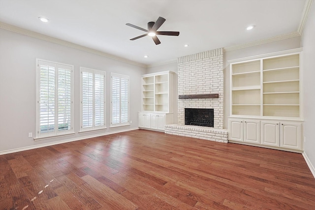 unfurnished living room with a ceiling fan, wood finished floors, a fireplace, and ornamental molding