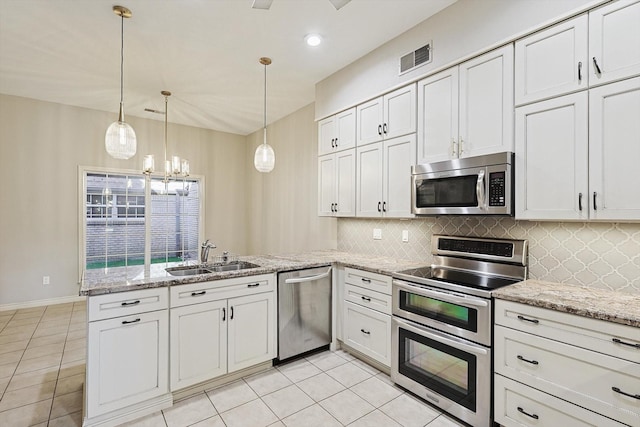 kitchen featuring a peninsula, appliances with stainless steel finishes, a sink, and light tile patterned floors