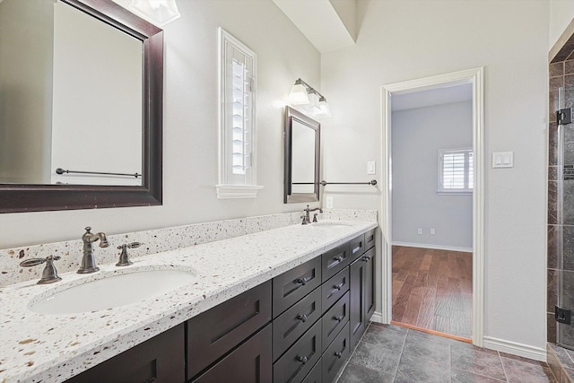 full bathroom with baseboards, a sink, and double vanity