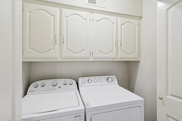 washroom with visible vents, independent washer and dryer, and cabinet space