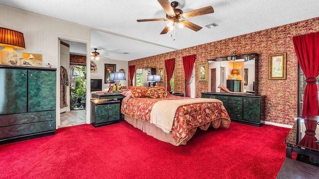 bedroom with a textured ceiling, carpet floors, visible vents, and ceiling fan