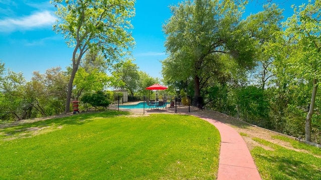 view of home's community with a yard, a swimming pool, and fence