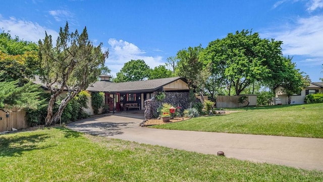 ranch-style house with driveway, fence, and a front yard