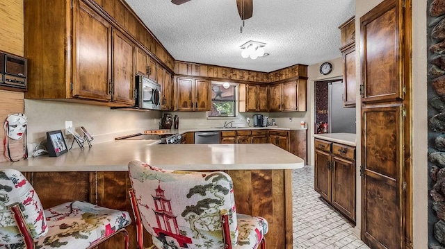 kitchen with stainless steel appliances, light countertops, a ceiling fan, a peninsula, and a textured ceiling