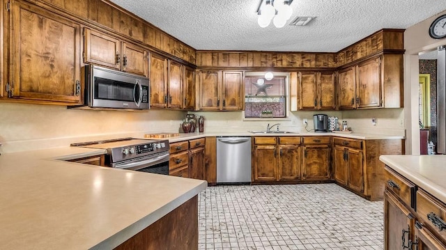kitchen featuring stainless steel appliances, a sink, a textured ceiling, visible vents, and light countertops