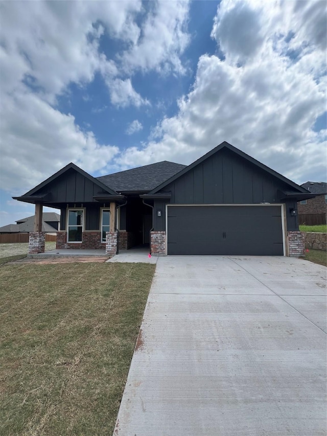 view of front of property featuring board and batten siding, a front yard, a garage, and concrete driveway
