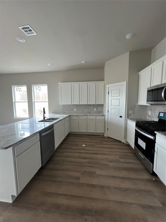 kitchen featuring stainless steel appliances, backsplash, visible vents, a sink, and a peninsula