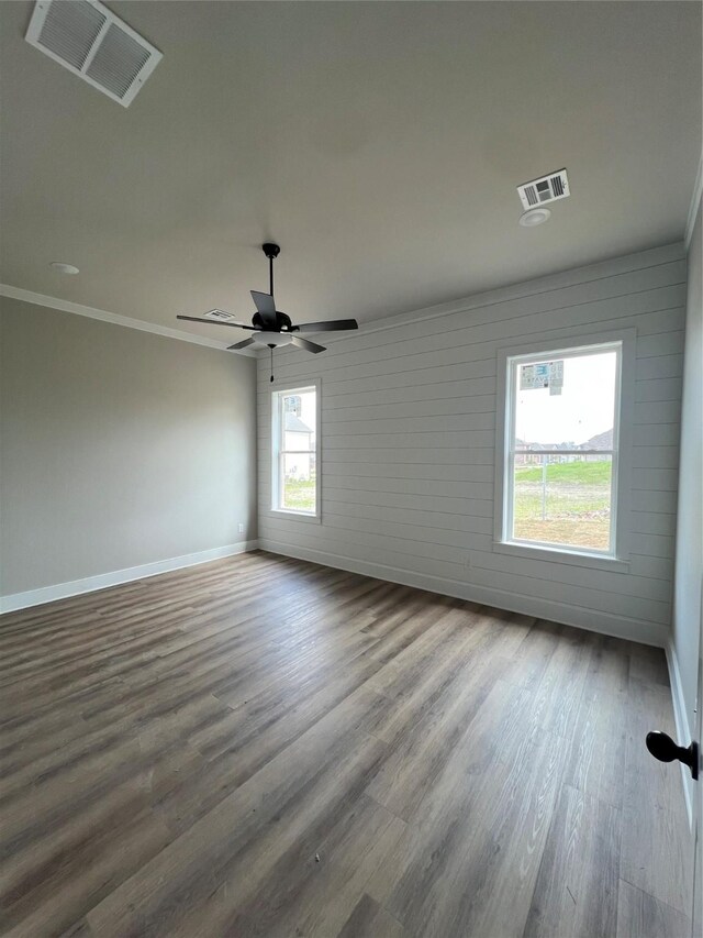 unfurnished room featuring wood finished floors, visible vents, baseboards, and ceiling fan