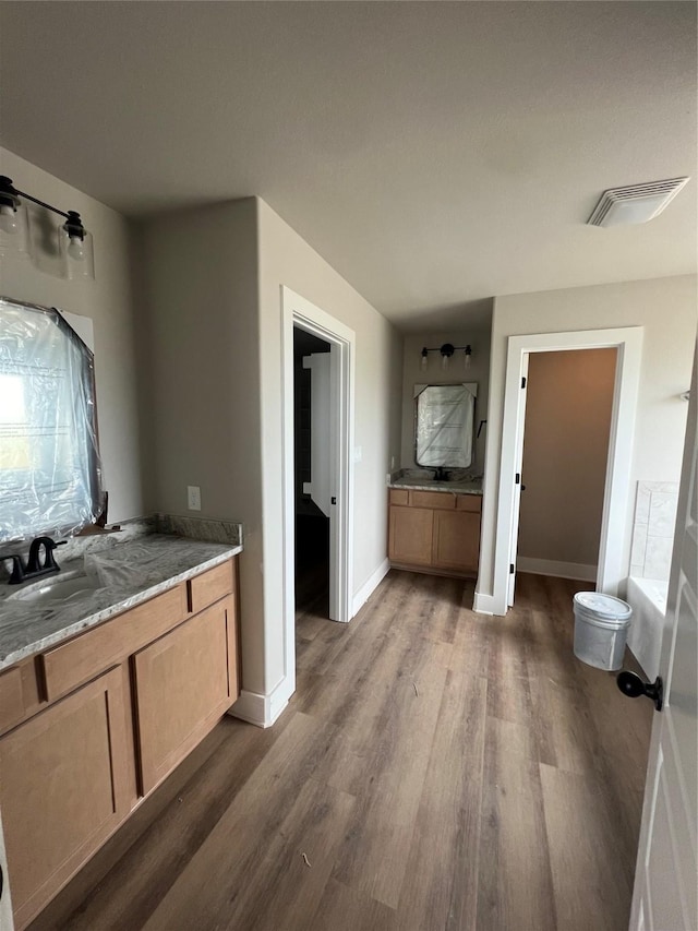 full bathroom featuring baseboards, vanity, wood finished floors, and visible vents