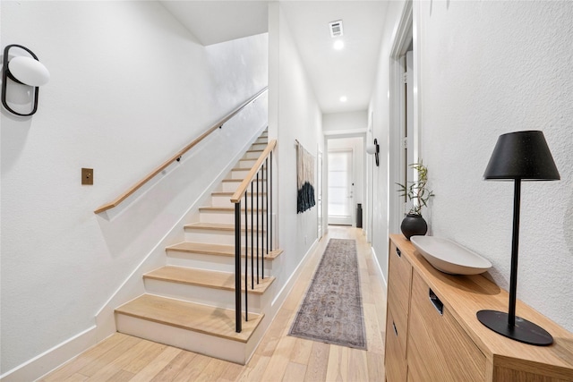 staircase with recessed lighting, wood finished floors, visible vents, and baseboards