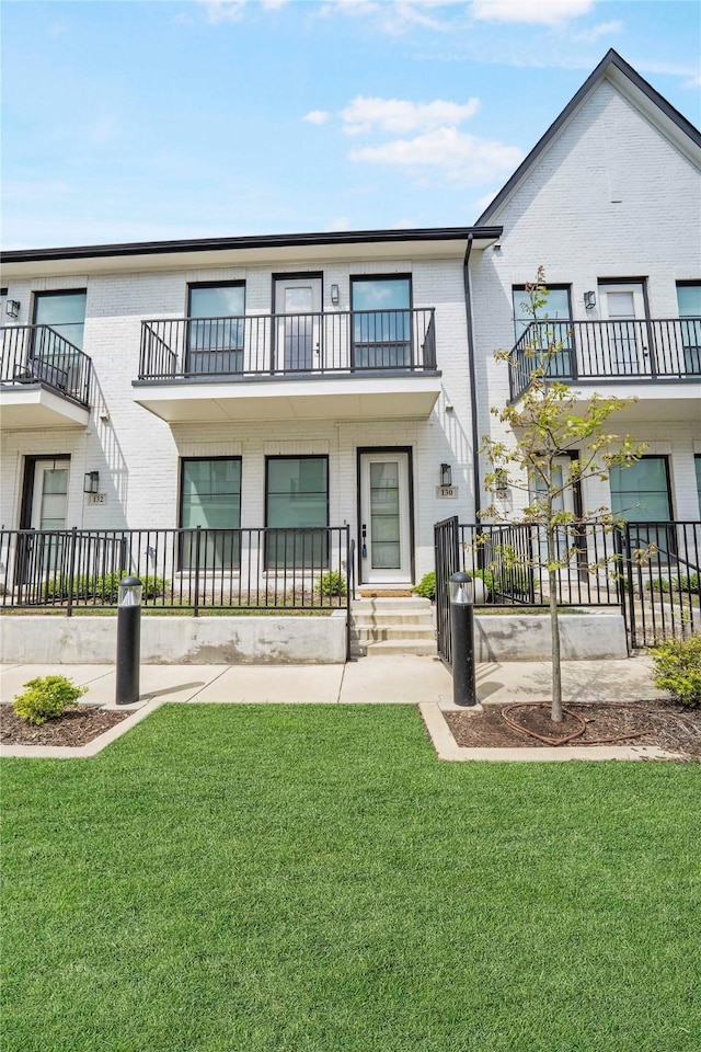 view of front of home featuring a front lawn, brick siding, and a balcony