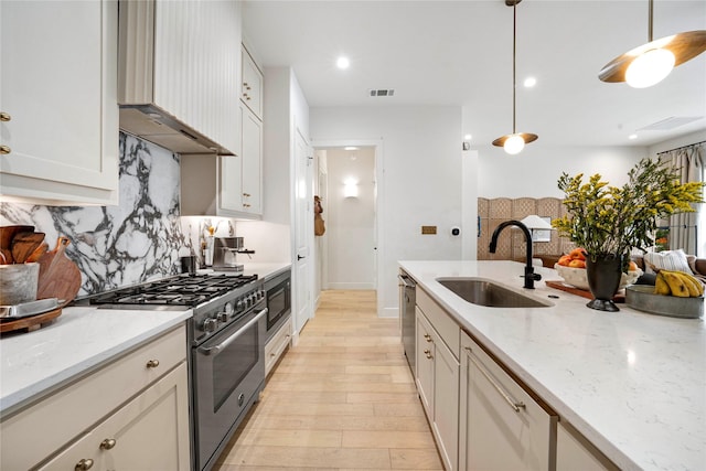 kitchen featuring stainless steel appliances, backsplash, visible vents, a sink, and wall chimney exhaust hood