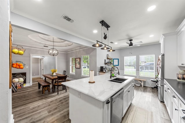 kitchen featuring stainless steel appliances, wood finished floors, a sink, a kitchen island with sink, and ceiling fan with notable chandelier
