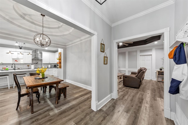 dining area with baseboards, ornamental molding, wood finished floors, and ceiling fan with notable chandelier
